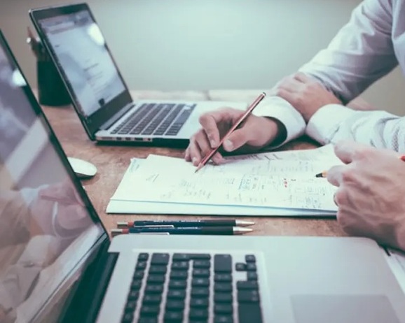 deux personnes qui échangent leurs idées sur papier et devant deux ordinateurs